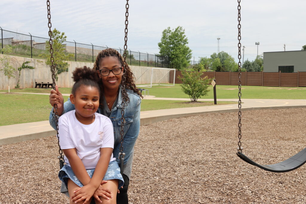 Shavonya Coleman smiles with one of her students as she pushes her on the swings during recess