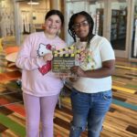 Two students hold their filmmaking award for stop motion animation